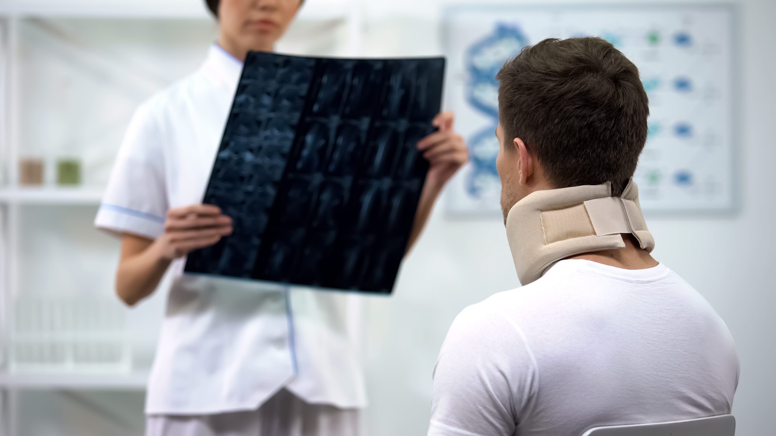 Man with consults with a physician looking at xray and considers a neck injury lawyer