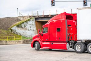 Red big rig turning into intersection represents importance of Alabama truck accident lawyer
