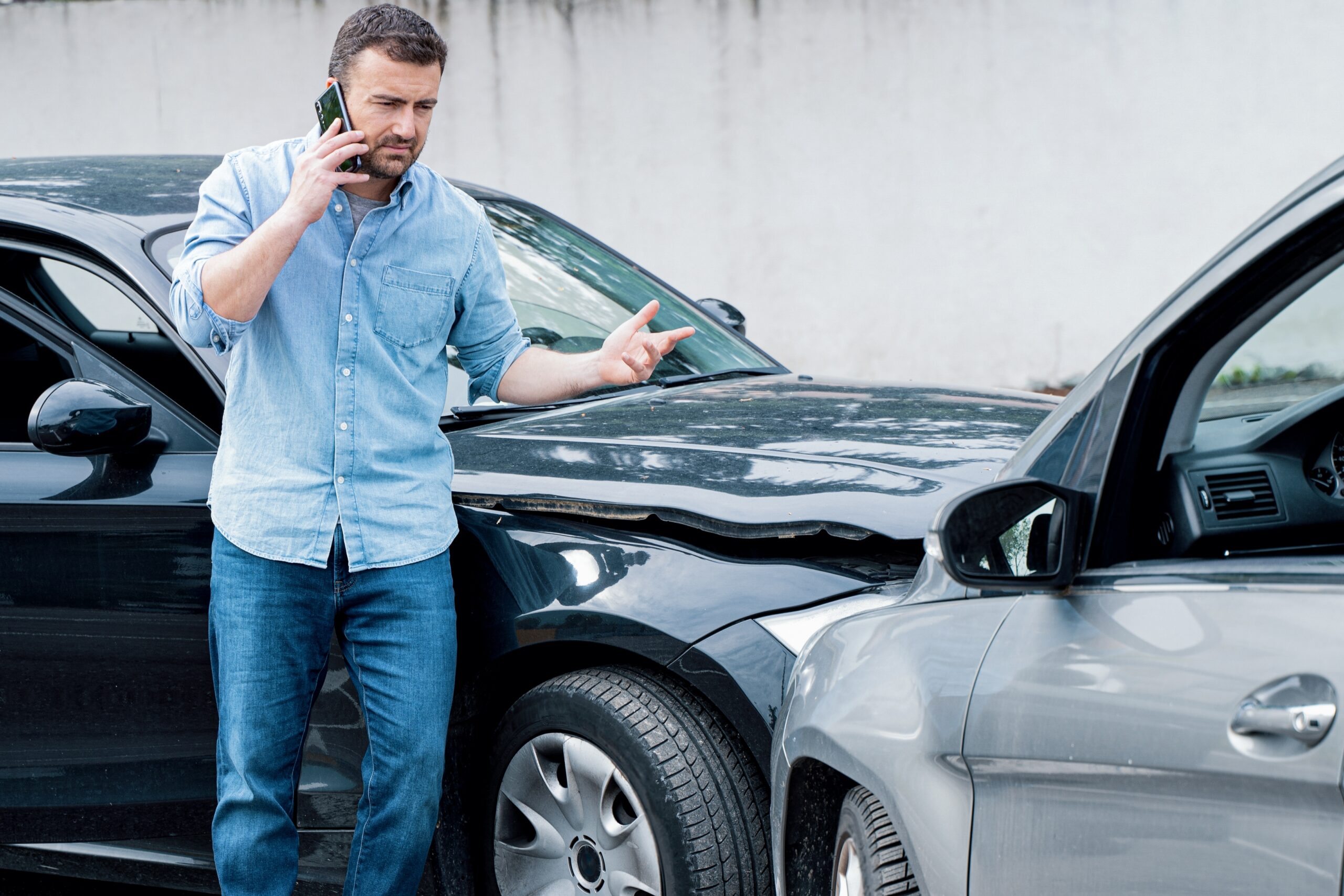 Man next to damaged car on phone asking his lawyer is Alabama a no fault state