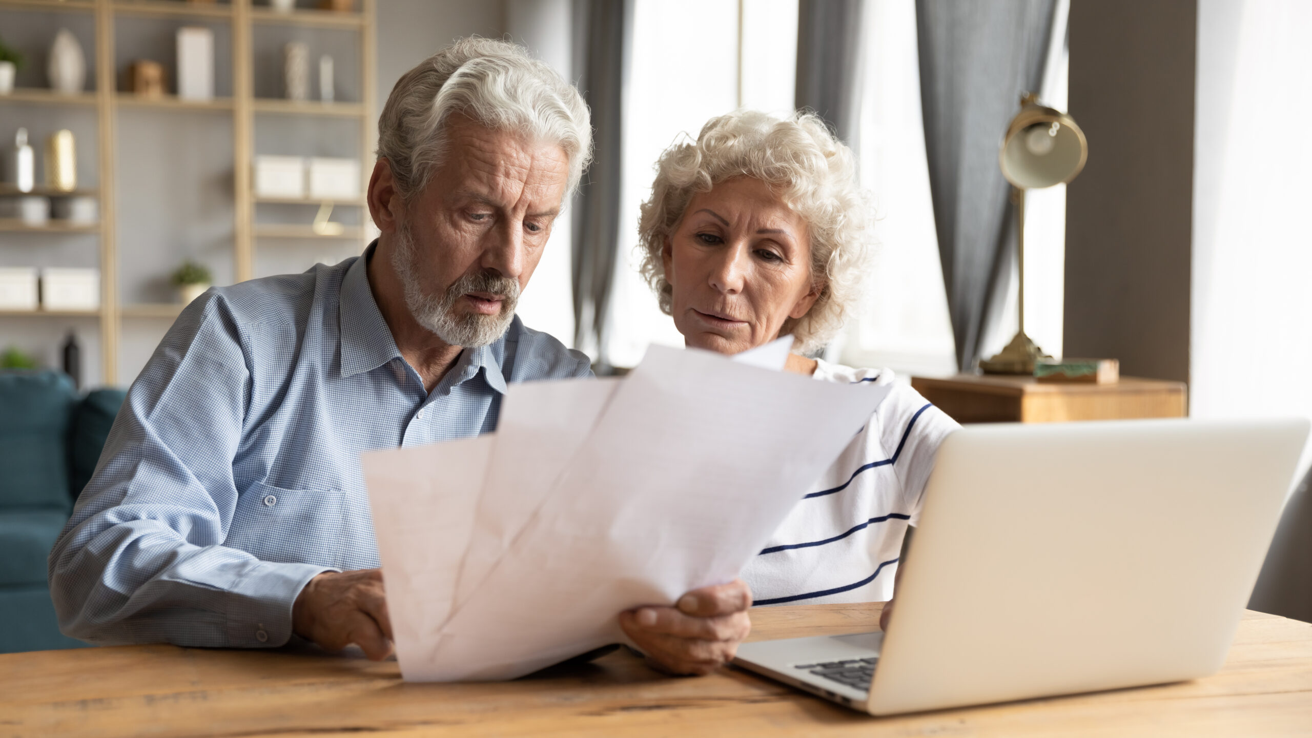 Senior couple looks over paperwork to determine should you accept an insurance company's settlement offer