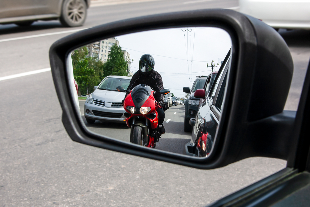 motorcyclist in rearview mirror to suggest the question, "is lane splitting legal in alabama"