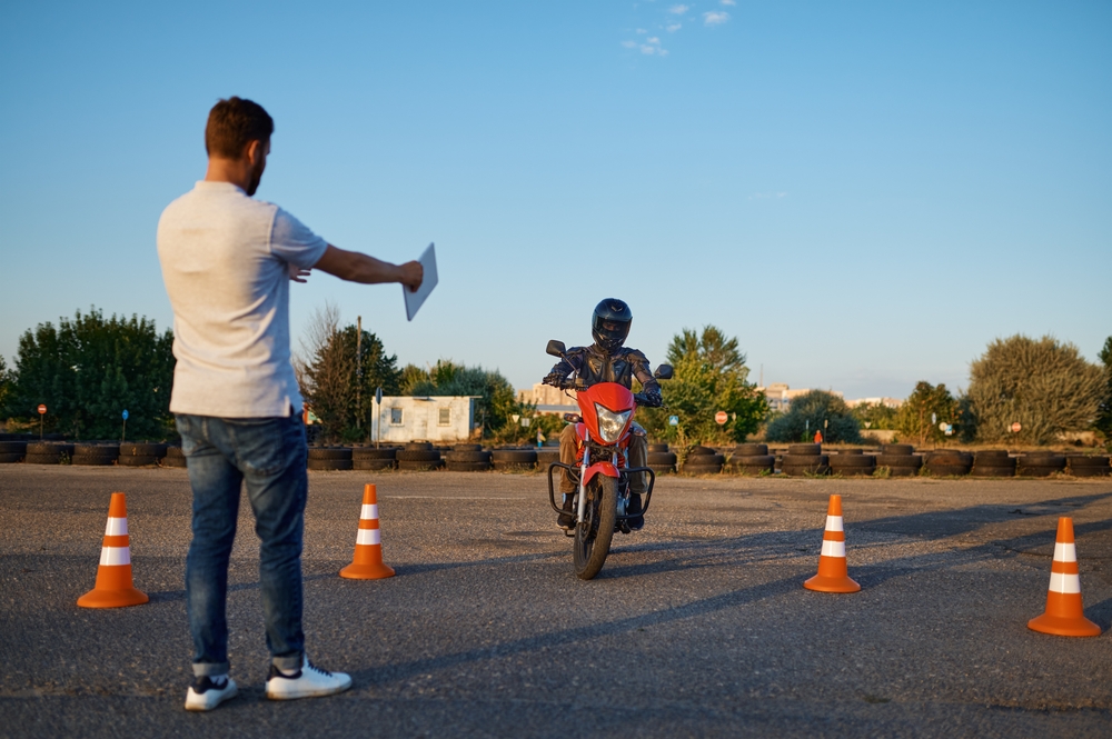 To show the answer to the questions "do you have to have a motorcycle license in Alabama?" this image shows someone taking their motorcycle driving test.