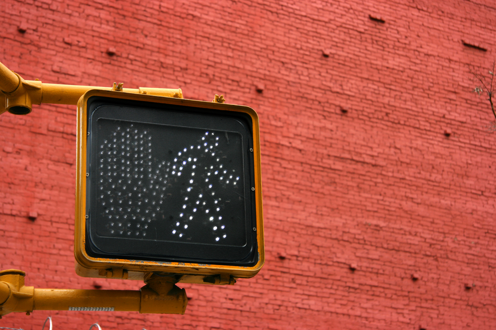 keep walking sign with red brick wall in background to represent importance of a pedestrian accident lawyer