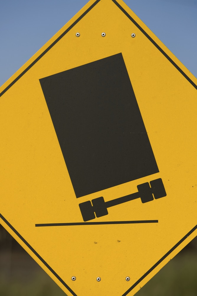 yellow roadsign of semi truck on two wheels